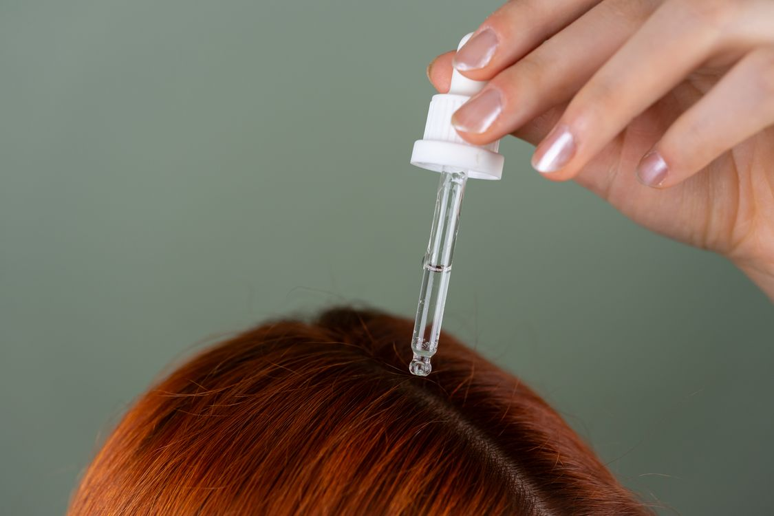 Precision dropper applying serum to the scalp, representing growth factor delivery and hair regeneration research