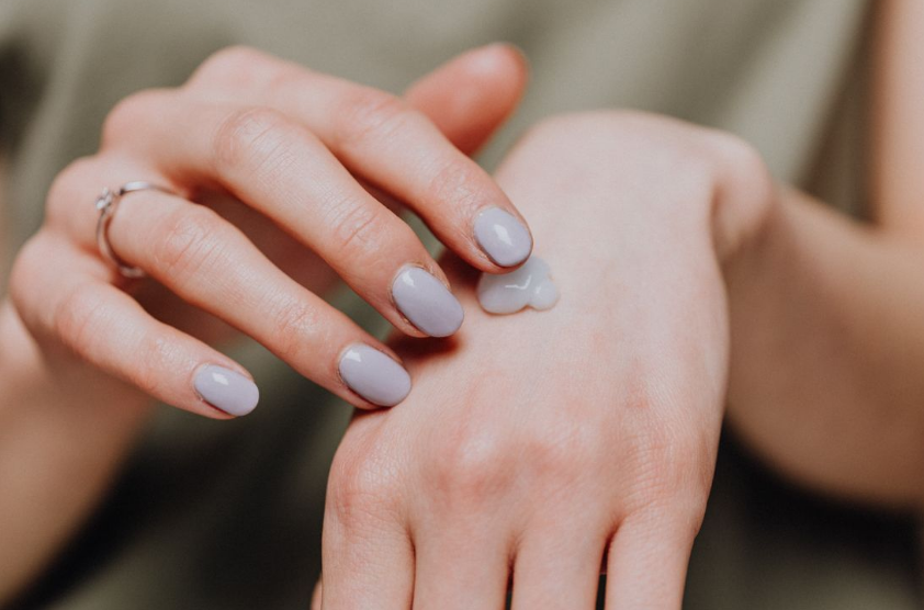 Woman applying hand cream representing tissue repair, skin regeneration, and restorative biological processes.